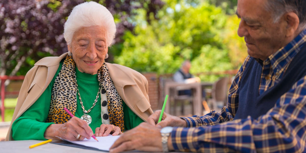 Two elderly people painting in the garden of a nursing home or retirement home
